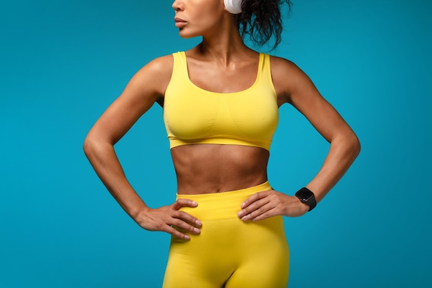 Unrecognizable athletic african american lady standing against blue studio background