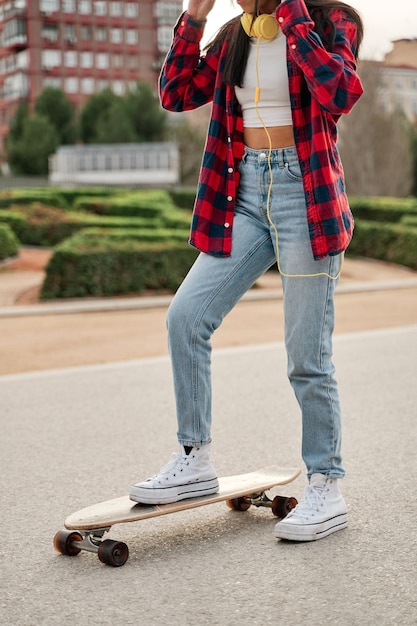 Unrecognizable atina woman in casual clothes skateboarding in the city