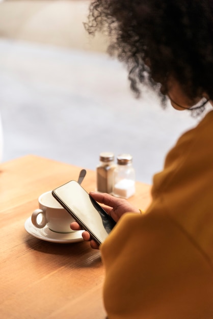 Unrecognizable beautiful afro american woman using mobile in the coffee shop. Communication concept.