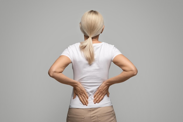 unrecognizable blonde woman suffering body ache or kidneys pain