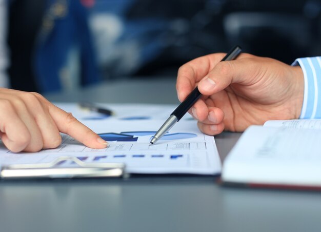 Unrecognizable business person analyzing graphs and taking notes