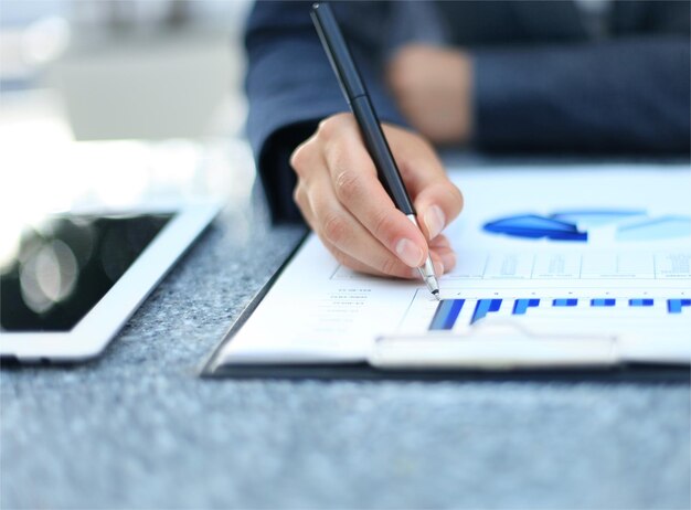 Photo unrecognizable business person analyzing graphs and taking notes