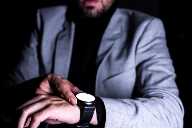 Фото Неузнаваемый бизнесмен, смотрящий на свои умные часы