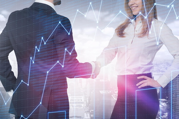 Unrecognizable businessman and smiling blonde businesswoman shaking hands standing over cityscape background with graphs. Concept of partnership. Toned image double exposure