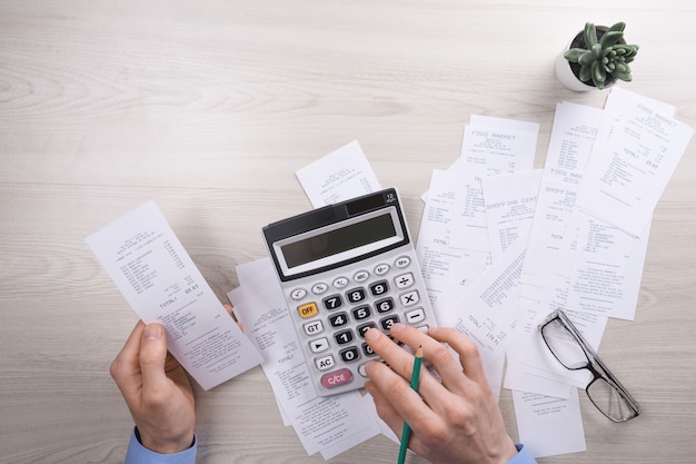 Unrecognizable businessman using calculator on desk office and writing make note with calculate about cost at home office. finance accounting concept. tax , shopping, cost management.