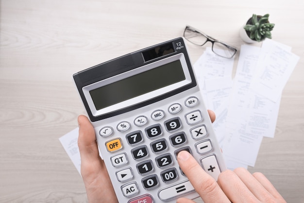 Unrecognizable businessman using calculator on desk office and writing make note with calculate about cost at home office