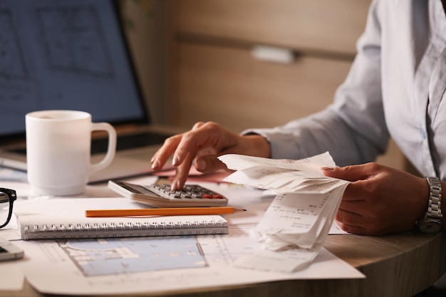 Unrecognizable businesswoman using calculator while going though her financial bills in the office