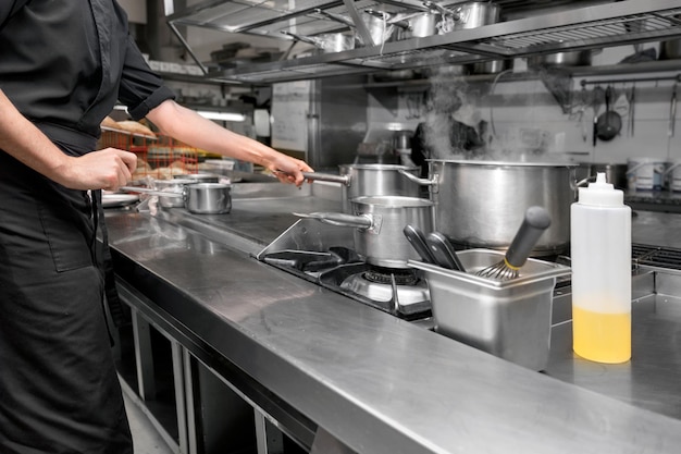 Foto chef irriconoscibile che cucina nella moderna cucina industriale