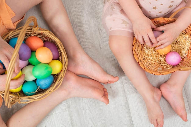 Photo unrecognizable children sitting on the floor with colorful easter eggs in two wicker baskets