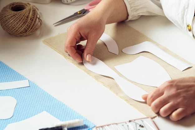 인식할 수 없는 근접 여성 재봉사가 작업장에서 섬유 시트에 종이 바느질 패턴 템플릿을 들고 배치