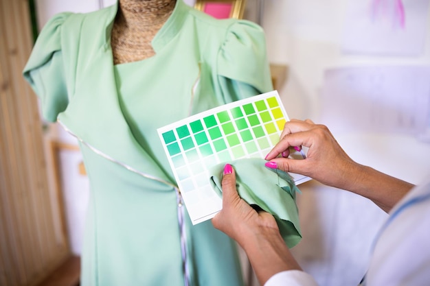 Фото Неузнаваемый дизайнер одежды держит ткань и зеленую цветовую палитру в помещении
