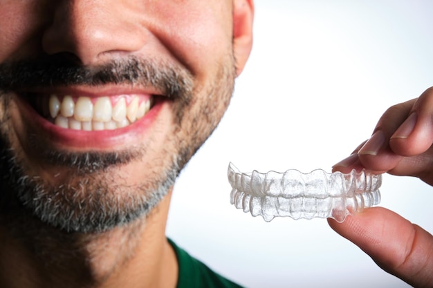 Unrecognizable dark-haired man with beard putting on transparent dental retainer