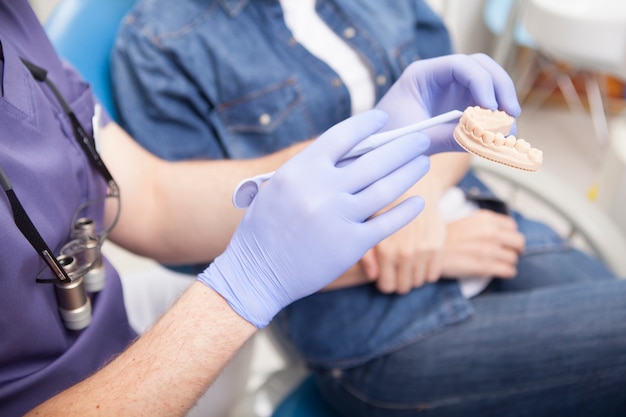 Unrecognizable dentist showing dental mold to the patient