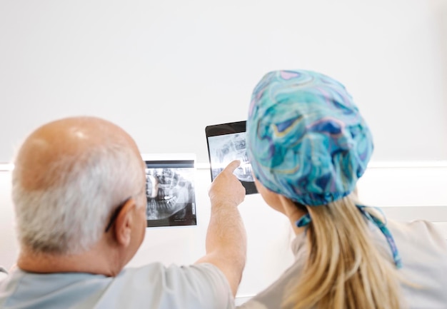 Unrecognizable dentists examining teeth X ray