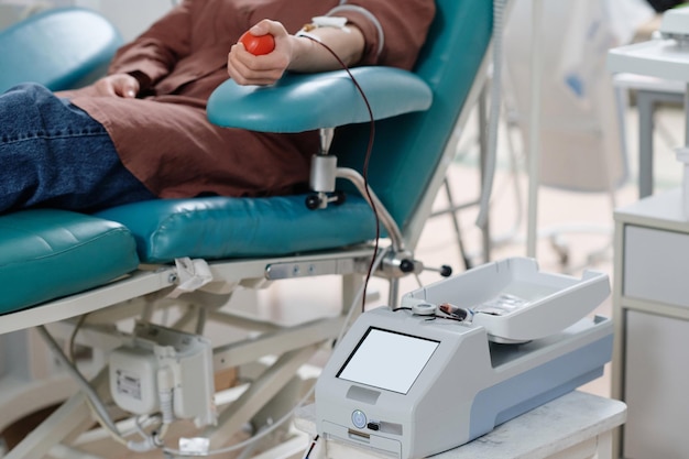 Unrecognizable Donor Relaxing on Procedure Chair During Blood Transfusion