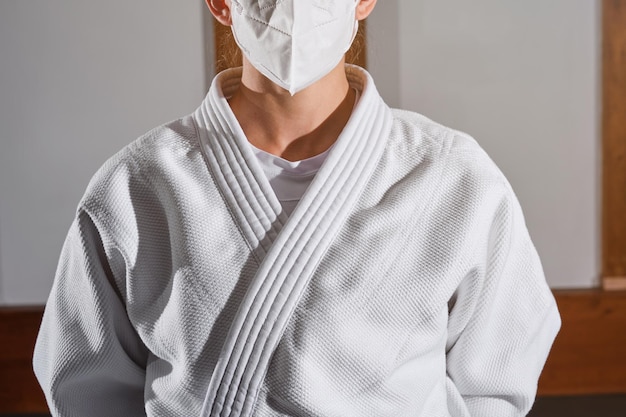 사진 전염병 상황에서 기모노를 입고 밝은 방에 서 있는 의료용 마스크를 쓴 알아볼 수 없는 여성