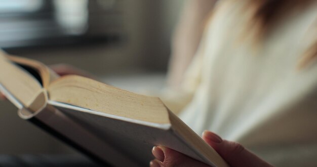 Foto femmina o studente irriconoscibile che gode di letteratura di intrattenimento o di libri di testo educativi imparare a studiare istruzione leggere libri rimanere a casa concetto