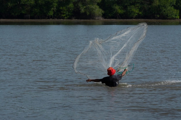 unrecognizable fisherman from the distance shore throwing fishing net to catch fish