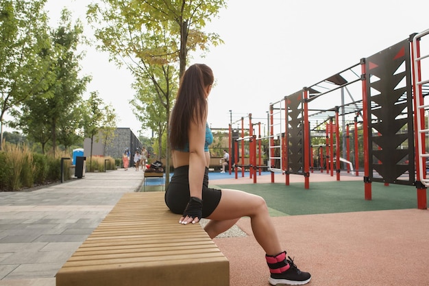 Unrecognizable fit woman sitting on a bench at street workout playground