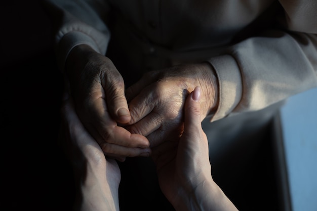 Unrecognizable grandmother and her granddaughter holding hands.