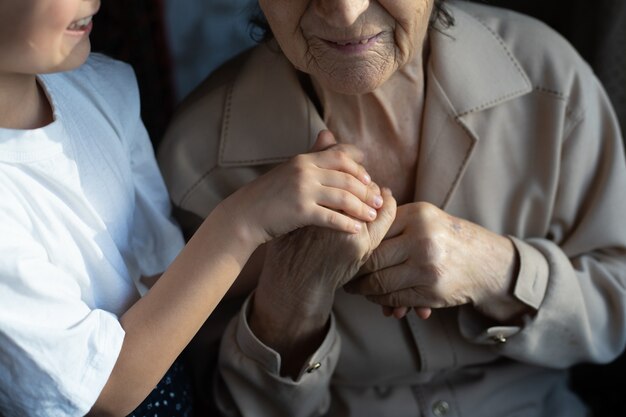 Unrecognizable grandmother and her granddaughter holding hands.