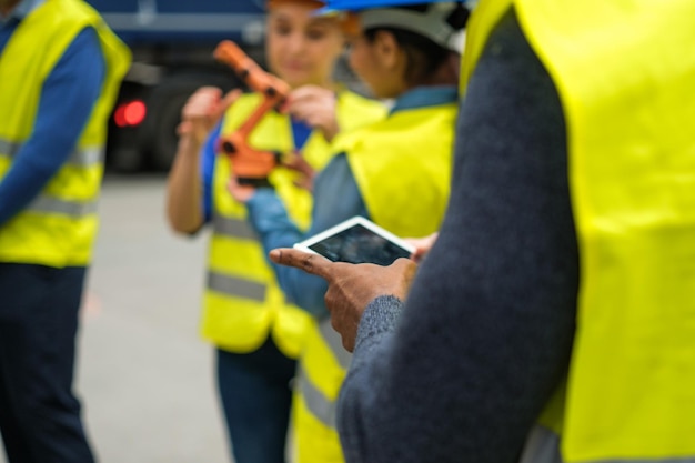 Unrecognizable group of factory workers focus on tablet