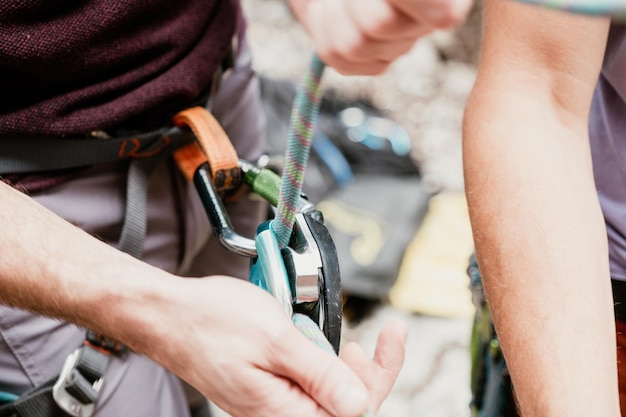 unrecognizable hand secures a carabiner in a rope harness