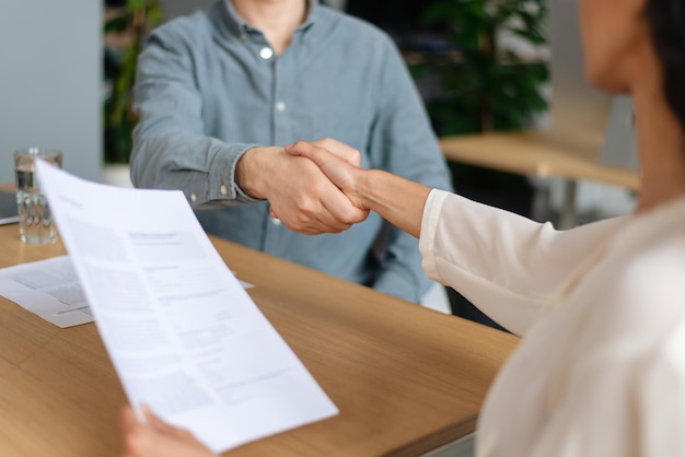 Responsabile delle risorse umane irriconoscibile che stringe la mano al candidato posto vacante di successo dopo il colloquio di lavoro a