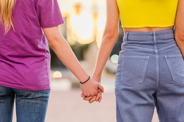 Unrecognizable lesbian couple holding hands young dating together in a female relationship