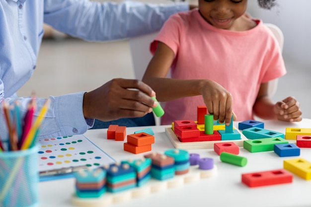 Unrecognizable little black girl exercising with female teacher