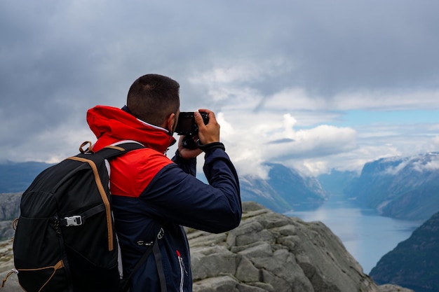 인상적인 Lysefjord의 Preikestolen에서 사진을 찍는 알아볼 수 없는 남성 사진사