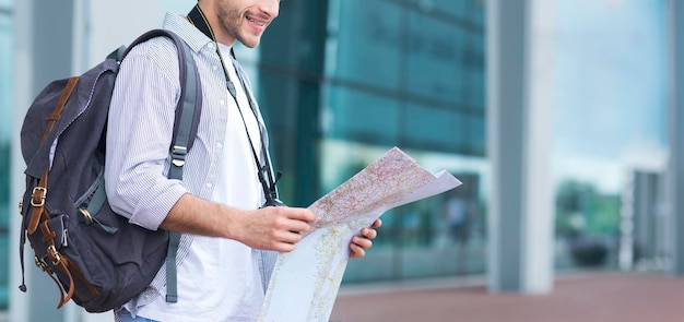 Unrecognizable male tourist with city map in hands standing\
near arport