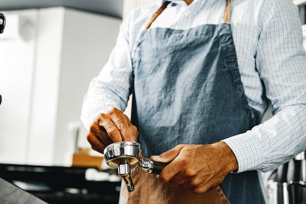 Unrecognizable man barista preparing coffee on professional coffee machine