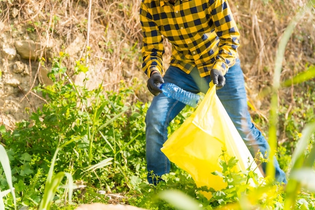 Фото Неузнаваемый мужчина собирает пластик в лесу