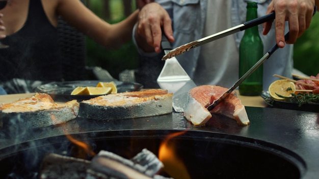 外で魚の調理を管理している認識できない男性 キッチン ツールを使用している男性