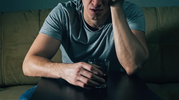 Unrecognizable man drinks whiskey from glass