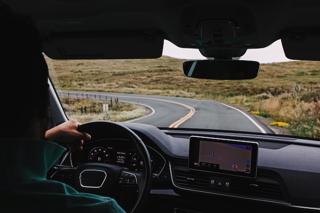 Photo unrecognizable man driving a car on an empty countryside road view from the inside of the car