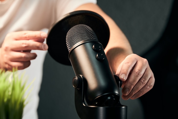 Unrecognizable man getting ready a black microphone equipment for a podcast