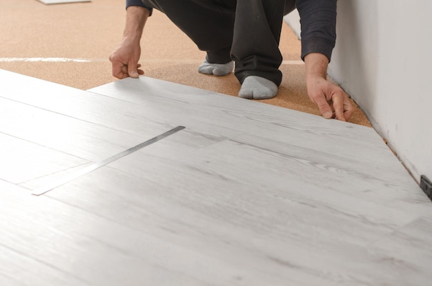 Photo unrecognizable man laying laminate flooring repair in the apartment professional laying of a floor covering a laminate laminate installation process