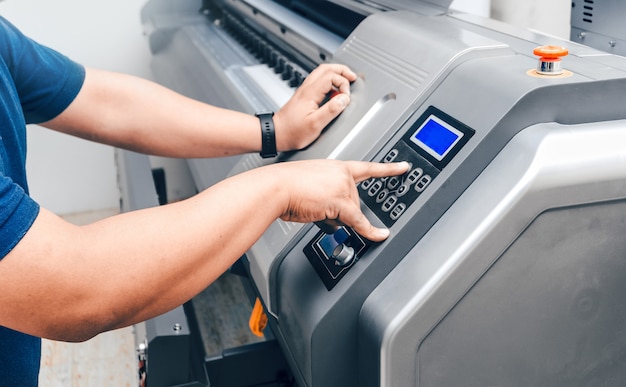 Unrecognizable man manipulating or controllingbuttons from a large format printing press