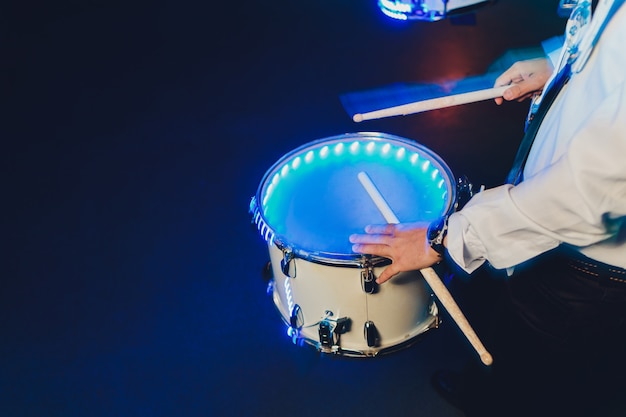 Unrecognizable man marching while playing drumming on drum.