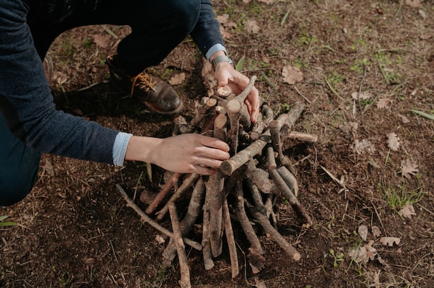 火をつけるために木の山を準備している認識できない男。キャンプ、自然なライフスタイルのコンセプト。