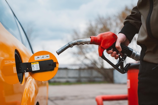 Uomo irriconoscibile che rifornisce di carburante l'auto dalla stazione di servizio che riempie il carburante della benzina della benzina in auto alla stazione di servizio concetto di prezzi elevati della benzina