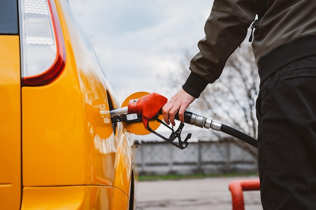 ガソリンスタンドで車にベンジンガソリン燃料を充填しているガソリンスタンドから車に燃料を補給している認識できない人ガソリン高価格コンセプト