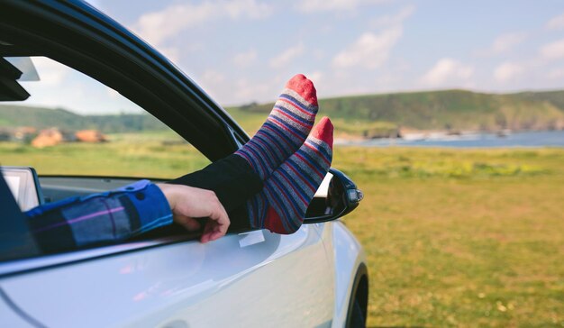 Unrecognizable man resting feet up sitting on the car