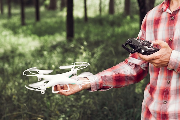 Unrecognizable man running drone with camera in forest.