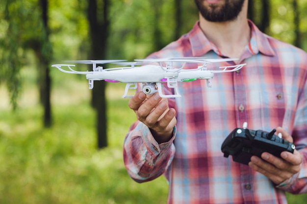 Unrecognizable man running drone with camera in forest.