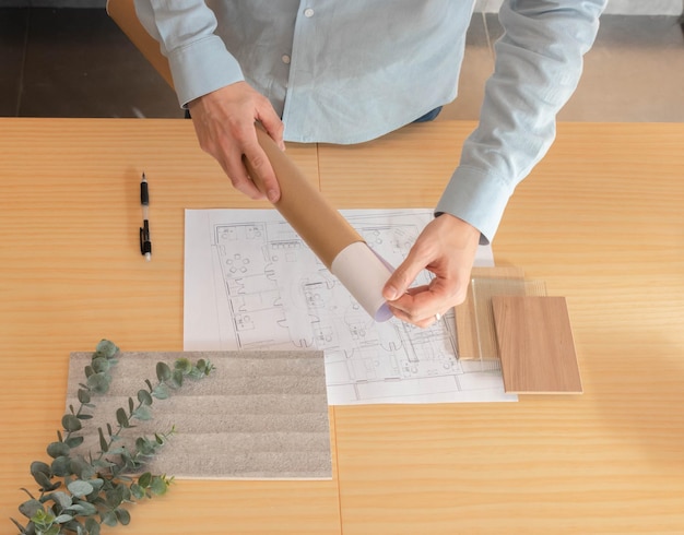 Unrecognizable man taking out an architectural plan of a plan\
holder