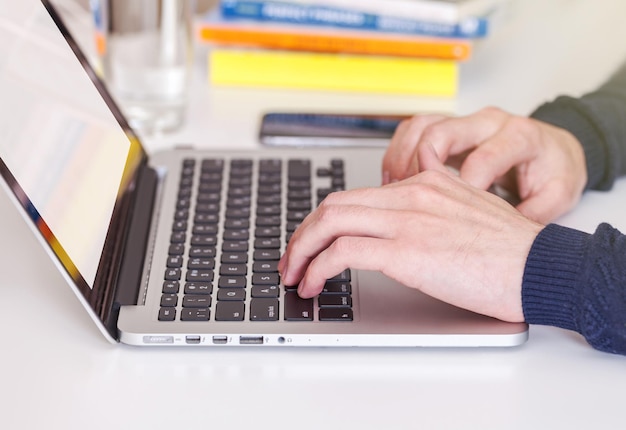 Unrecognizable man using a modern portable computer on an white table