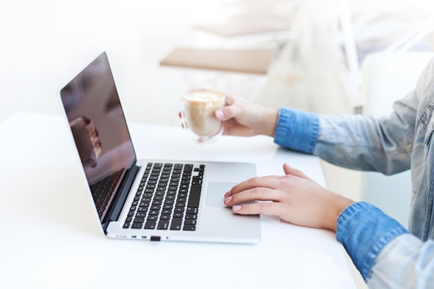 Unrecognizable man using a modern portable computer on an white
table